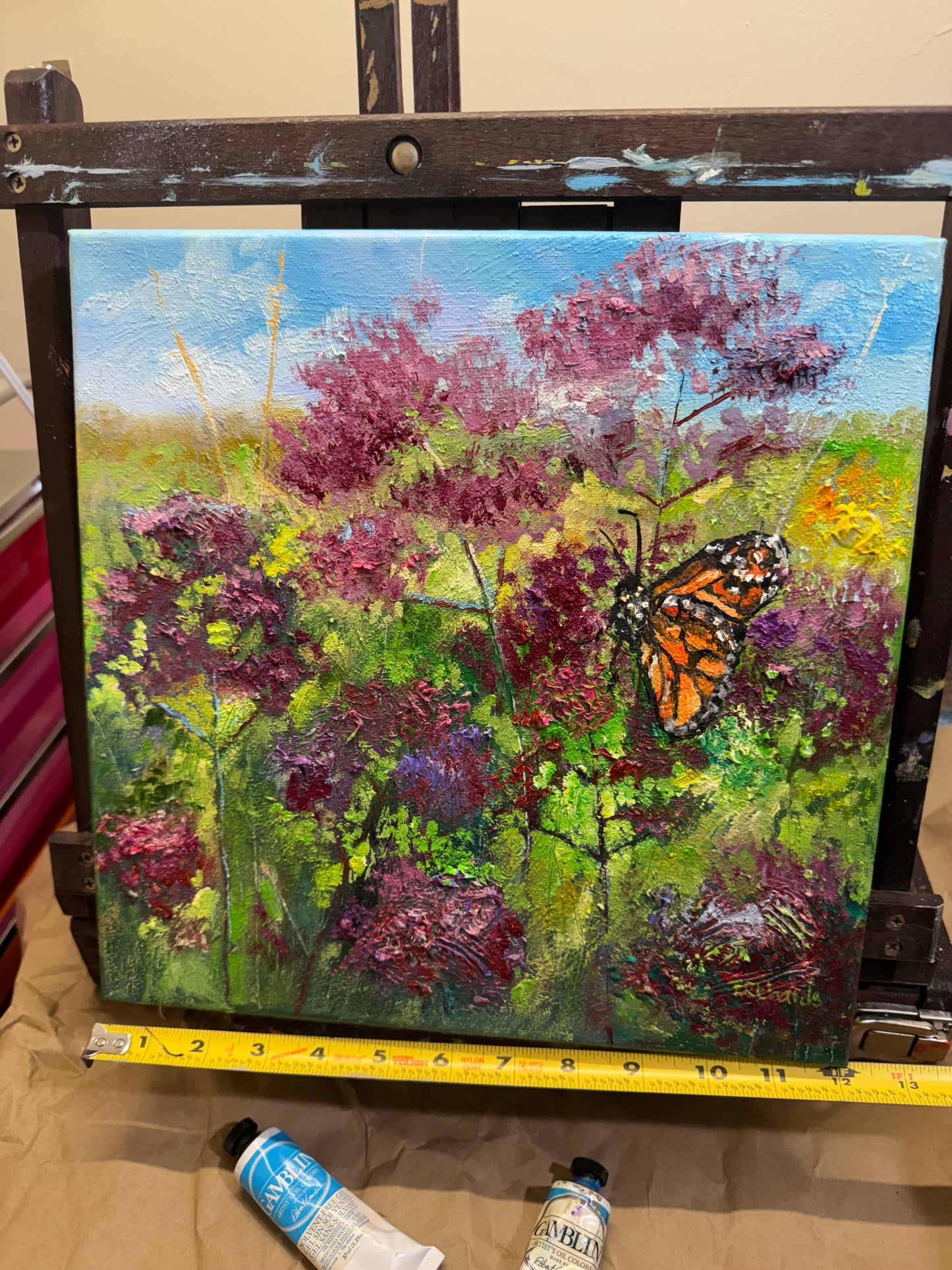 Painting of a butterfly on flowers with a measuring tape beside it